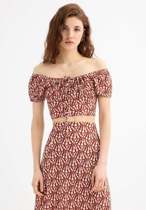 Cropped top azul claro con estampado de flores, mangas abullonadas por debajo del hombro y detalle de lazo en la parte delantera, combinado con una falda de cintura alta a juego.