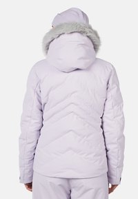 Lilla pufferjakke med chevron-syninger, faux fur-detalje på huen og lange ærmer. Glat, polstret tekstur for isolering.
