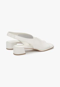 Białe skórzane buty typu slingback z kwadratowym noskiem, niskim obcasem w kształcie bloczku, gładką teksturą i wycięciami po bokach.