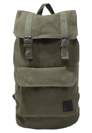 Olivengrøn lærredsrugtaske med fold-over top, justerbare stropper, metalspænder og en forlomme med klap. Tekstureret overflade.