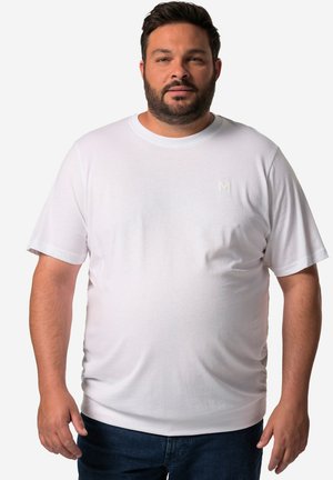 Weißes T-Shirt mit kurzen Ärmeln aus weichem Material, mit Rundhalsausschnitt und dezent geprägtem "M"-Logo auf der Brust. Kombiniert mit dunkler Jeans.