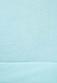 Ljusblått tyg med slät stickad textur ovanför och ribbad stickad textur nedanför.