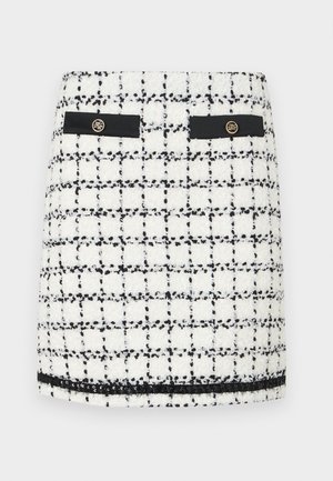 Tweed mini skirt in white and black, featuring a grid pattern, black accents, two front pockets, and gold button details.