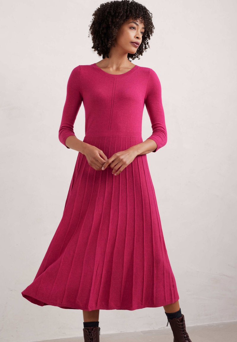 Abito lavorato a maglia fucsia con maniche lunghe, texture a costine e gonna plissettata, caratterizzato da un corpino aderente e scollatura rotonda.
