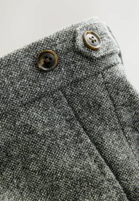 Gray textured fabric with a woven pattern, featuring two brown buttons at the waistband and a neatly stitched crease line.