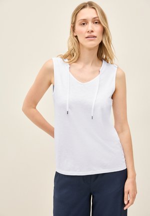 Top bianco senza maniche con scollatura a V e coulisse, realizzato in tessuto morbido, abbinato a pantaloni blu navy. Design semplice e rilassato.