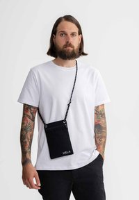 Zwarte stoffen schoudertas met een gestructureerd oppervlak en geborduurd "MELA"-logo. Voorzien van een gestreepte schouderband en metalen hardware accenten.