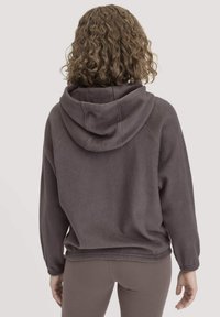 Donkergrijze fleece hoodie met een grote capuchon, geribde manchetten en zoom. De stof lijkt zacht en textuur te hebben, ontworpen voor comfort en warmte.