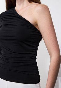 Black one-shoulder top made of soft, stretchy fabric with gathered details along the body. Smooth texture with a fitted silhouette.