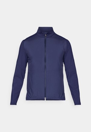 Chaqueta ligera azul marino con cuello alto, cremallera frontal completa y mangas largas. Fabricada con un tejido técnico suave y con un acabado ligeramente texturizado.
