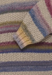 Gros plan sur une manche de pull tricoté multicolore avec des rayures horizontales bleu, violet, rose, jaune, vert et beige.