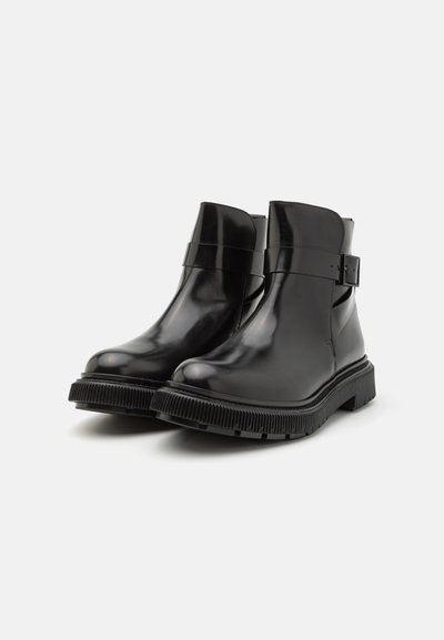 Botine din piele neagră, cu un finisaj neted, bot rotund, accent cu cataramă pe lateral și talpă din cauciuc cu striații pentru aderență.