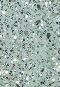 Mátově zelená tkanina zdobená různě velkými reflexními stříbrnými flitry uspořádanými v rozptýleném vzoru. Hladký povrch s lesklými akcenty.