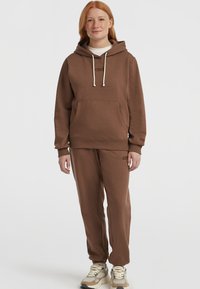 Felpa marrone e pantaloni abbinati realizzati in materiale morbido, con tasca frontale, cappuccio con coulisse e dettaglio del logo ricamato.