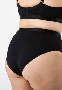 Svart högmidjad underkläder med en jämn textur och elastisk midjeband som har varumärkeslogotyp. Enkelt, sömlöst design utan mönster.