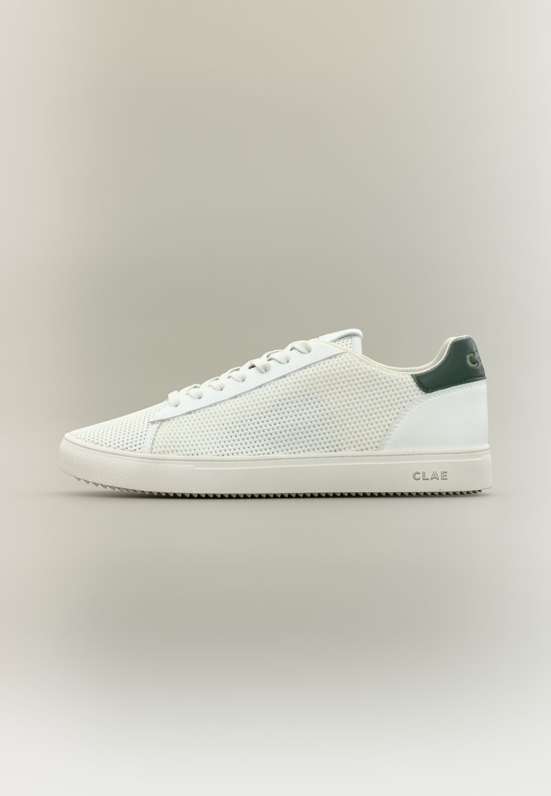 Λευκό sneaker χαμηλού προφίλ με πλευρές από δίχτυ, λευκά κορδόνια, λαστιχένια σόλα και σκούρο πράσινη ταμπέλα στη φτέρνα με το λογότυπο "CLAE".