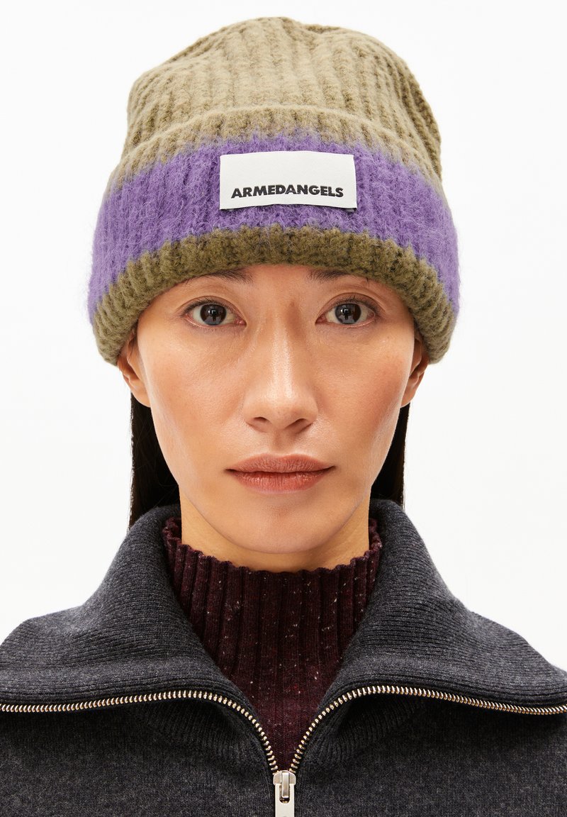 Bonnet en laine tricotée de couleur vert olive et violet, avec une texture côtelée et une étiquette blanche portant le logo "ARMEDANGELS." La coupe est ajustée à la tête.