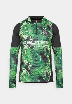 Camisa atlética de manga larga con un patrón de camuflaje verde, acentos negros, cremallera frontal y logo a la altura del pecho para la identificación de la marca.