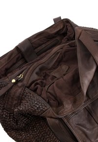 Bruine leren handtas met tekstuurlijke geweven accenten, voorzien van een pluche stoffen interieur, een ritsvak en stikdetails.
