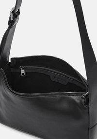 Zwarte leren schoudertas met een zachte textuur, ritssluiting en een binnenzak. Verstelbare band bevestigd aan de tas.