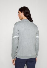 Sudadera gris de mezcla de algodón, con mangas largas, escote redondo y rayas blancas en las mangas. Corte informal con puños acanalados.