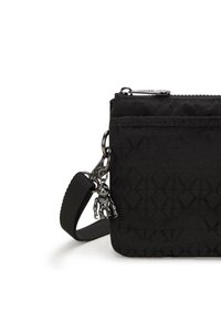 Schwarze Stofftasche mit gesteppter Textur, Reißverschlussverschluss und einem kleinen Metallanhänger. Verfügt über einen verstellbaren Trageriemen für Komfort beim Tragen.