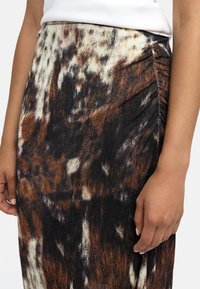 Spódnica do kolan z teksturowanej tkaniny w brązowy i czarny wzór zwierzęcy. Sk gathered na boku dla dodatkowej głębi.