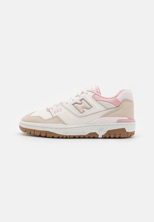 Sneaker bianco e rosa chiaro con tomaia in camoscio e pelle, dettagli perforati e suola beige. Presenta un logo visibile e il numero di modello.