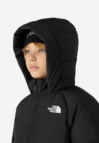 Chaquetón negro de plumas con un alto cuello y una gran capucha. Presenta un zipper central y un logo blanco en la zona del pecho izquierdo.