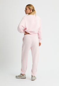Rosa passende Sweatshirts und Jogginghosen, weicher Stoff, lockere Passform, elastischer Bund, gerippte Knöchel, kombiniert mit silbernen Sportschuhen.