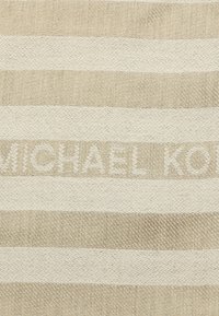 Tessuto a righe beige e crema con una finitura testurizzata e il nome "MICHAEL KORS" intrecciato nel tessuto con un filo chiaro.