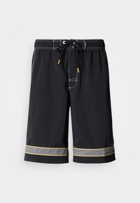 Μαύρο μαγιό με κορδόνι στη μέση, αντίθετες λευκές ραφές και κίτρινα διακοσμητικά στο τελείωμα, κατασκευασμένο από ομαλό, ελαφρύ ύφασμα.