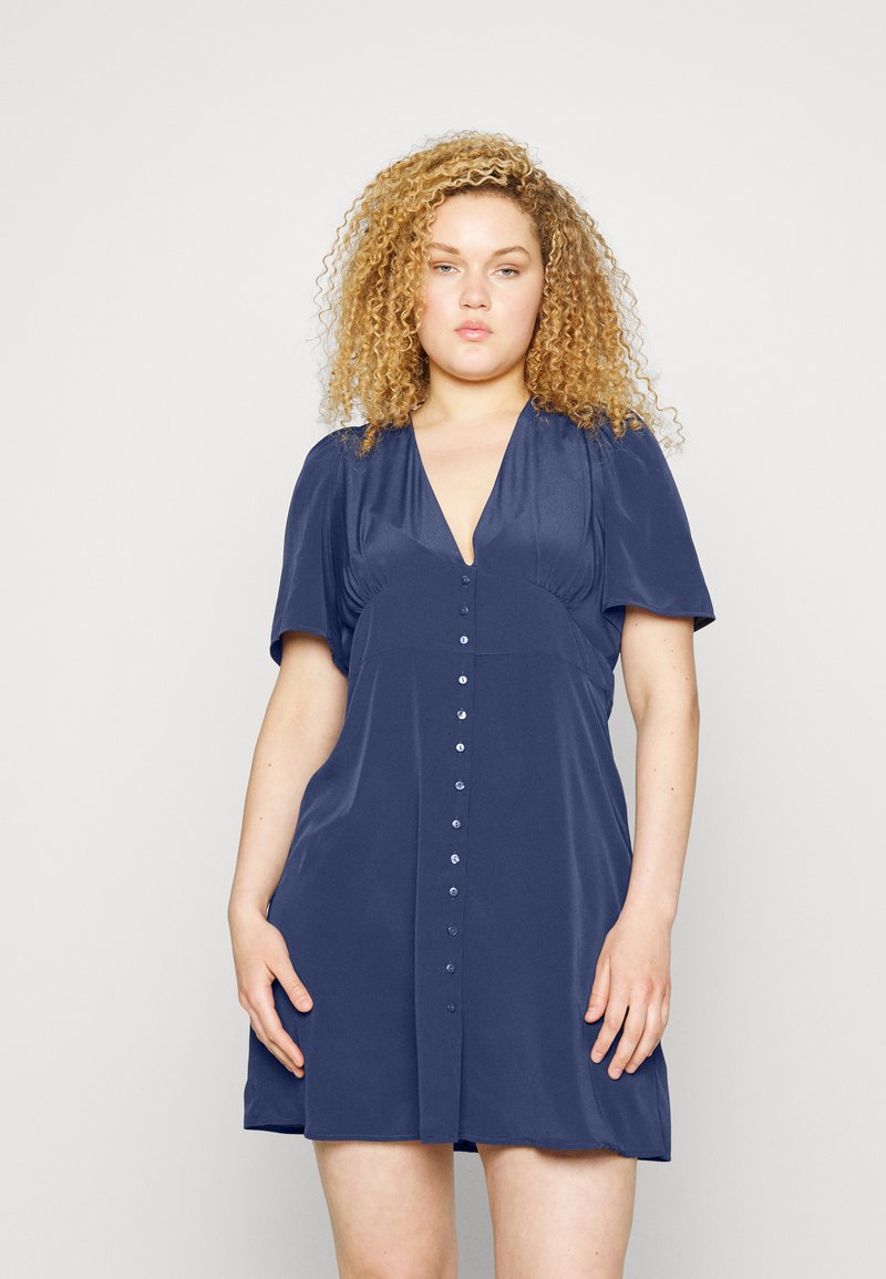 Vestido curto azul-marinho com decote em V, mangas curtas bufantes e fecho de botão na frente; tecido suave com brilho mínimo.