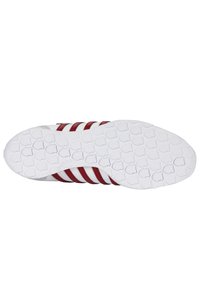 Weiße Sportschuhsohle mit einer strukturierten Gummibasis. Mit drei roten Streifen und einem glatten, geschwungenen Design. Dezentes Logo-Detail sichtbar.