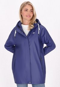 Violetinė nesuvaržanti lietaus striukė su gobtuvu, priekyje užtrauktuku, reguliuojamais raišteliais ir šoninėmis kišenėmis; glotni tekstūra ir laisvas kirpimas.
