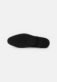 Semelle de chaussure noire avec une surface texturée, un bord lisse et un petit talon. Matériau durable, conçu pour l'adhérence et la stabilité.