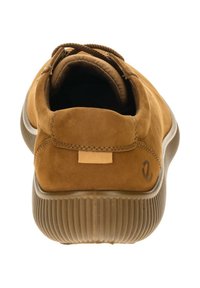 Sneaker in suede marrone con suola in gomma testurizzata, forma arrotondata e lacci marroni. Presenta un'etichetta piccola sul tallone e dettagli di cucitura minimali.