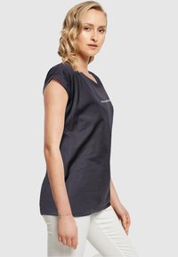 Marineblå bomulds-t-shirt med en afslappet pasform, korte rulleærmer og rund halsudskæring. Har et hvidt hashtag-grafik på forsiden.