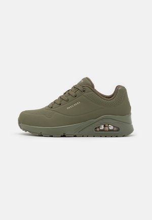 Buty sportowe Skechers w kolorze oliwkowej zieleni, z przodem na sznurowadła, wyściełanym kołnierzem, perforowanymi detalami i widoczną poduszką powietrzną w podeszwie.