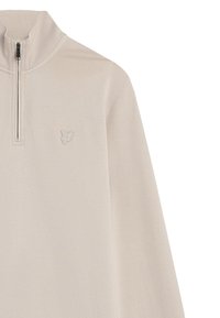Lichtbeige pullover met een halve rits kraag, gemaakt van zacht materiaal. Heeft een klein geborduurd logo op de linkerborst. Lange mouwen.