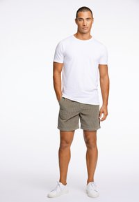 Camiseta de algodón blanca, pantalones cortos a rayas olivo y zapatillas blancas. Enfocado en un diseño y ajuste casual, con texturas suaves. Fondo limpio.