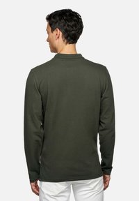 Polo shirt a maniche lunghe di colore verde scuro in tessuto di cotone. Presenta un colletto a camicia e un orlo dritto. Vista posteriore, senza motivi o accenti visibili.