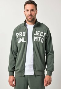 Giacca zip-up verde oliva realizzata in tessuto morbido. Presenta la scritta bianca in caratteri a blocco "PROJECT MTD" sul fronte. Polsini e orlo a costine.