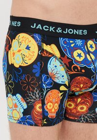 Herre boksershorts med sort bakgrunn, prydet med fargerike hodeskalle- og blomsterdesign. Materialet er elastisk med en kontrasterende midje.