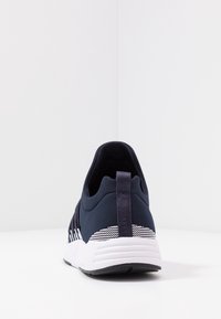 Granatowy but sportowy o smukłym designie, teksturowana cholewka, biała podeszwa środkowa oraz pasek z detalami na pięcie. Pętelka z tyłu.