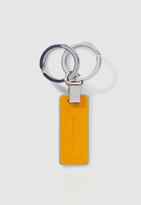 Sleutelhanger met twee metalen ringen en een rechthoekig leren label in oranje met blauwe randen; voorzien van een geperst merknaam.