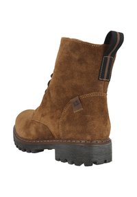 Bottine ankle en suède marron avec une finition texturée, tirant noir rayé et semelle en caoutchouc robuste. Elle présente un design cousu le long des bords.