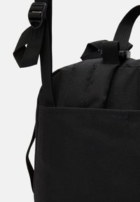 Sac à dos en tissu noir avec bretelles ajustables et panneau dorsal rembourré, présenté en vue rapprochée.