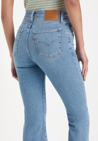 Jean en denim bleu clair avec une coupe droite, une étiquette arrière en cuir et deux poches arrière avec un détail de couture subtil.