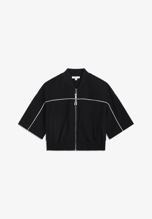 Kort zwart jack met korte mouwen, witte piping langs de borst en een rits aan de voorkant. Beschikt over een geribde tailleband en een zachte stoftextuur.